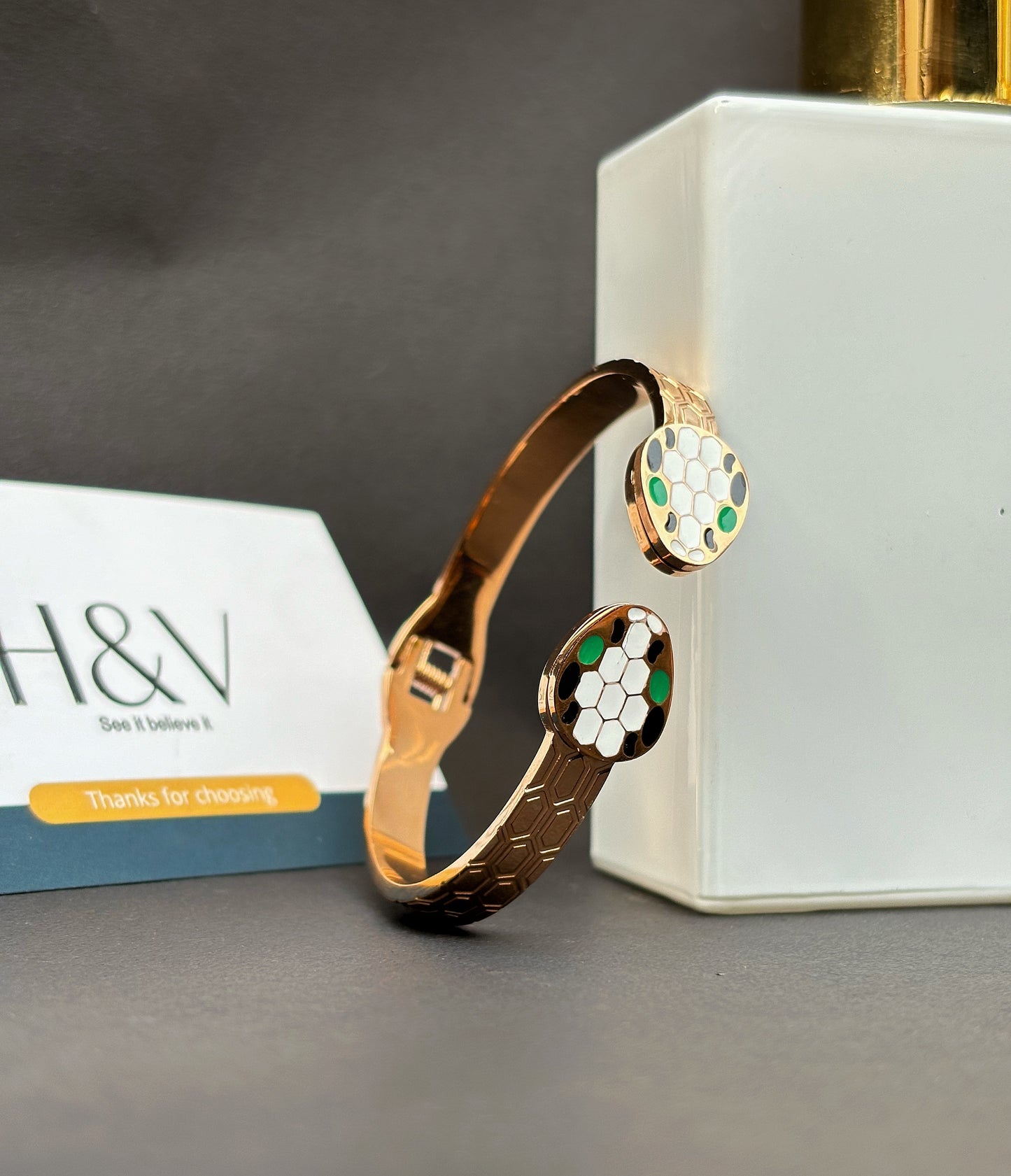 A golden bracelet with a green white & black snake design by hvjewellery.in